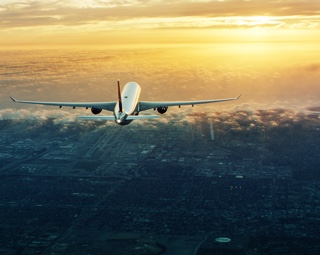 Airplane flying toward sunset.