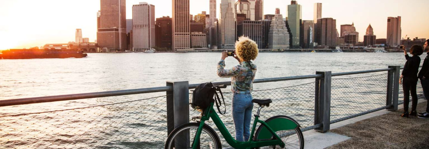 Woman with bike photographing cityscape