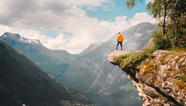 Man hiking to the edge of a mountain cliff