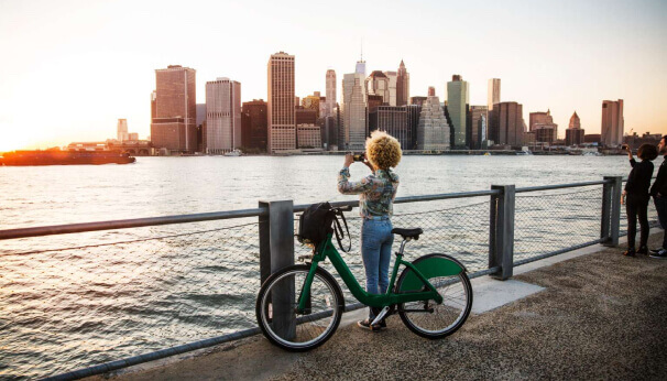 Woman with bike photographing a cityscape
